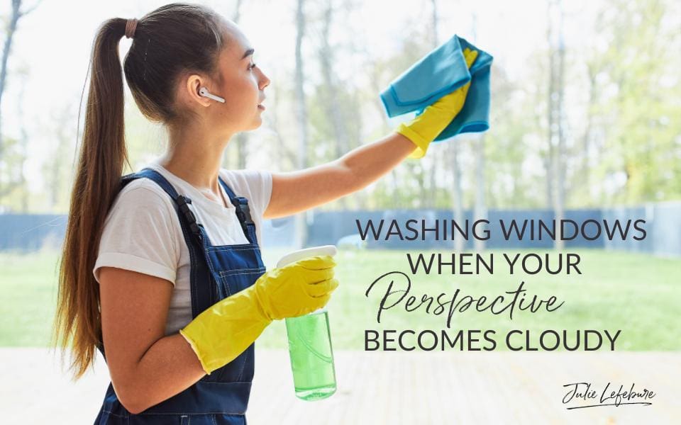 Washing Windows When Your Perspective Becomes Cloudy | woman in overalls with cleaning gloves on washing a window with a cloth and spray bottle