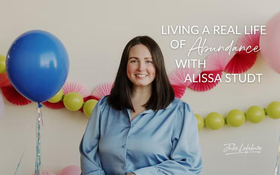 Living a Real Life of Abundance with Alissa Studt | Alissa Studt in light blue blouse next to a blue balloon in front of maroon streamers and yellow-green string of balloons